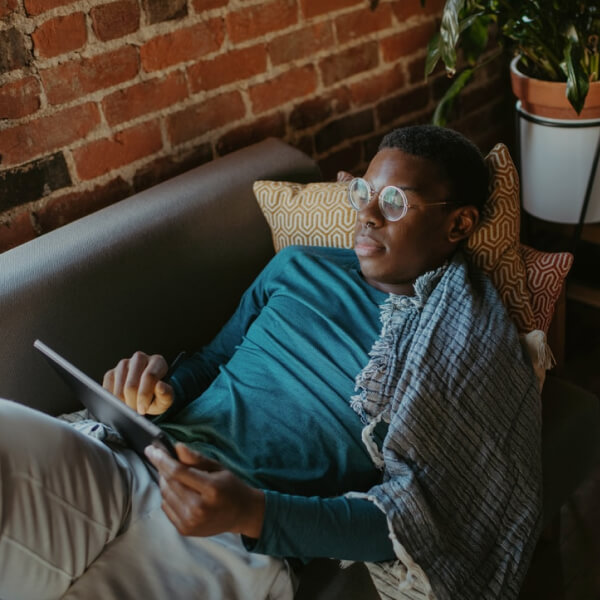 person laying on couch on tablet