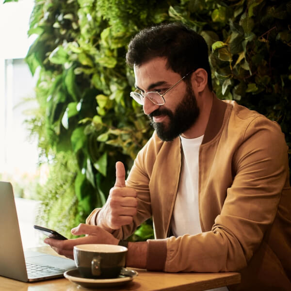 Man at coffee shop checking his business account on his mobile device